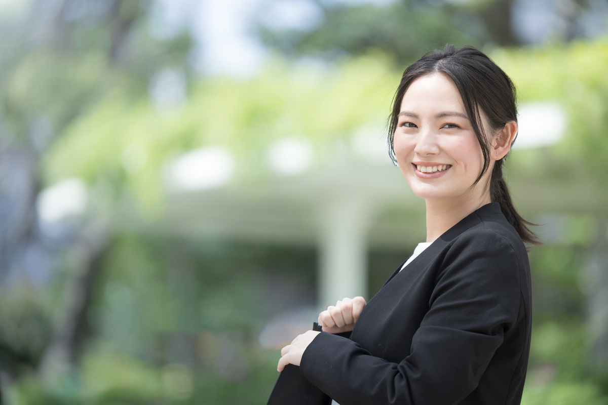 屋外でスーツを着た若い女性営業が振り返る