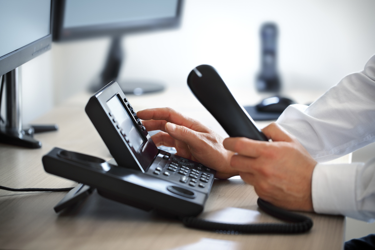 コミュニケーション、お問い合わせ、およびカスタマーサポートのため電話のキーパッドをダイヤルしている。